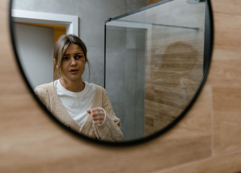 Banyo aynasında kendine endişeyle bakan kadın