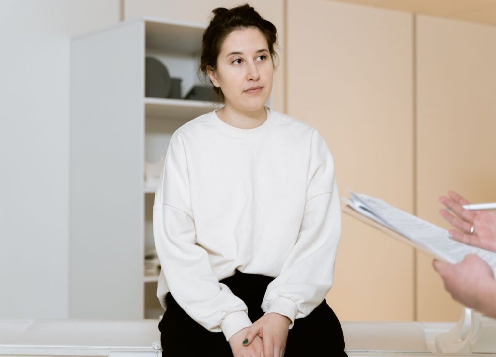 Göğüs küçültme ameliyatı öncesi muayene odasında doktorunu dinleyen hasta